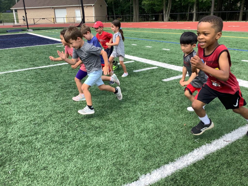 a group of young boys taking off into a run on a turf field